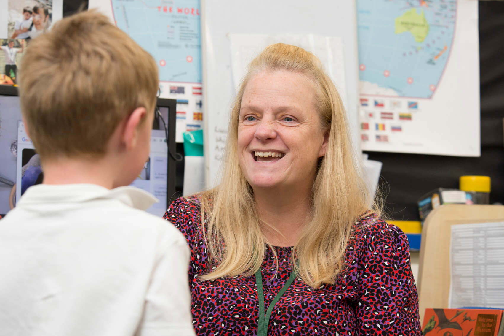 Primary school teacher laughing with a pupil 
