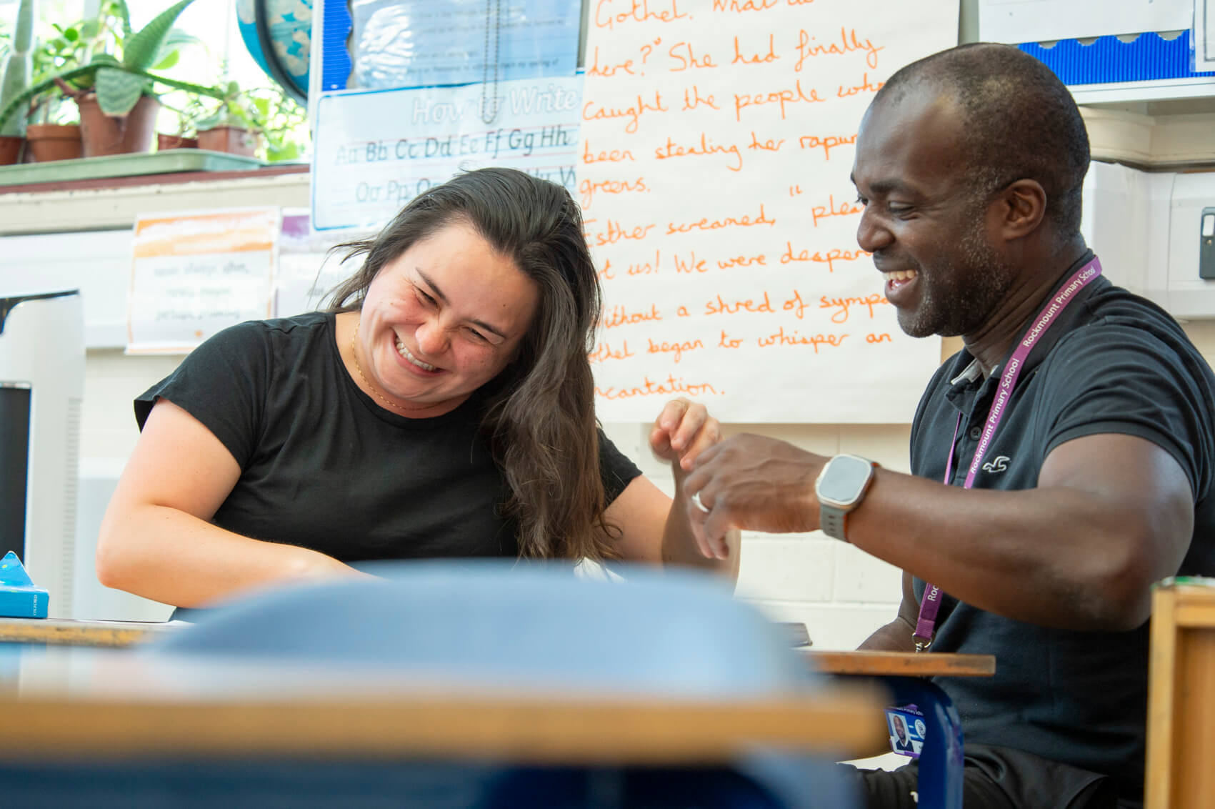 A man and woman laughing in a classroom 