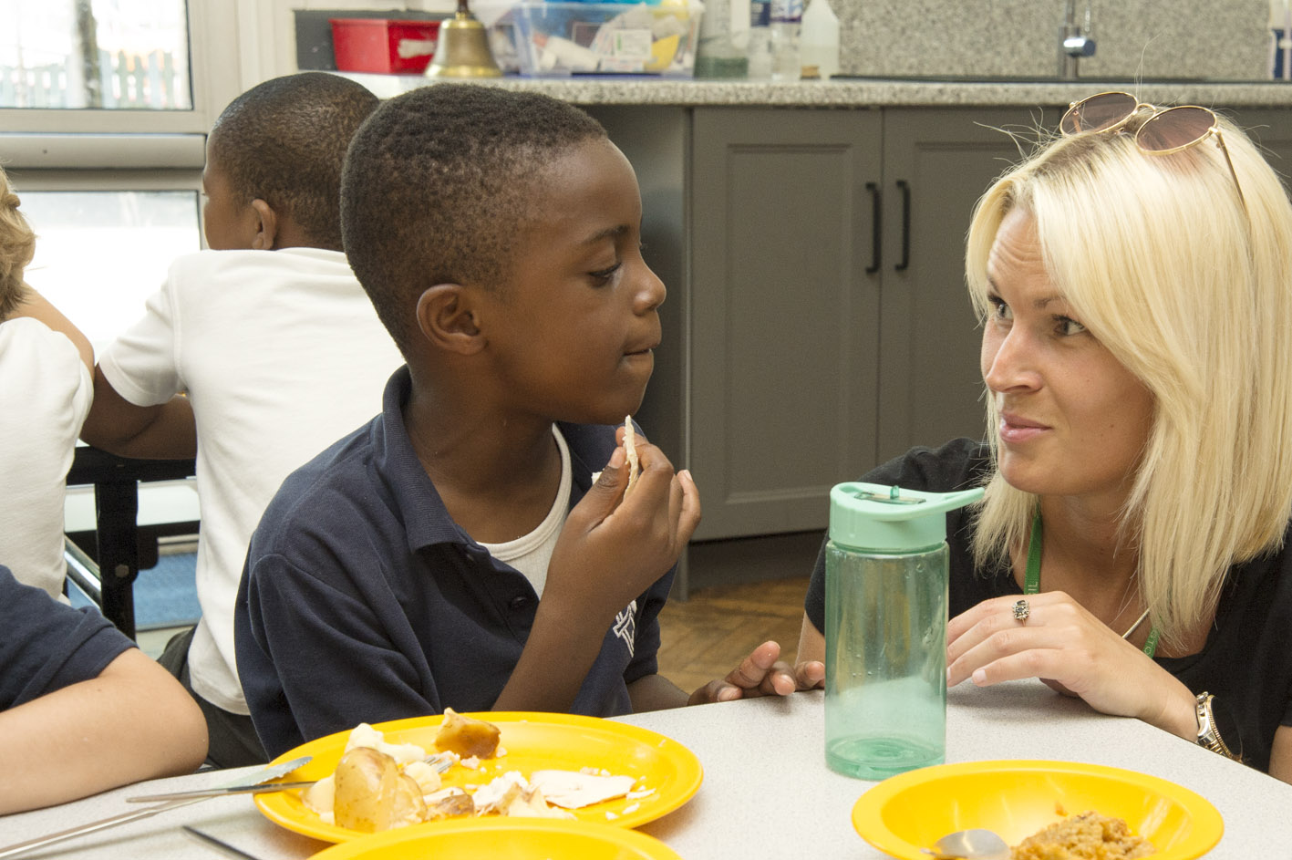 A teacher speaking to a pupil at school lunchtime