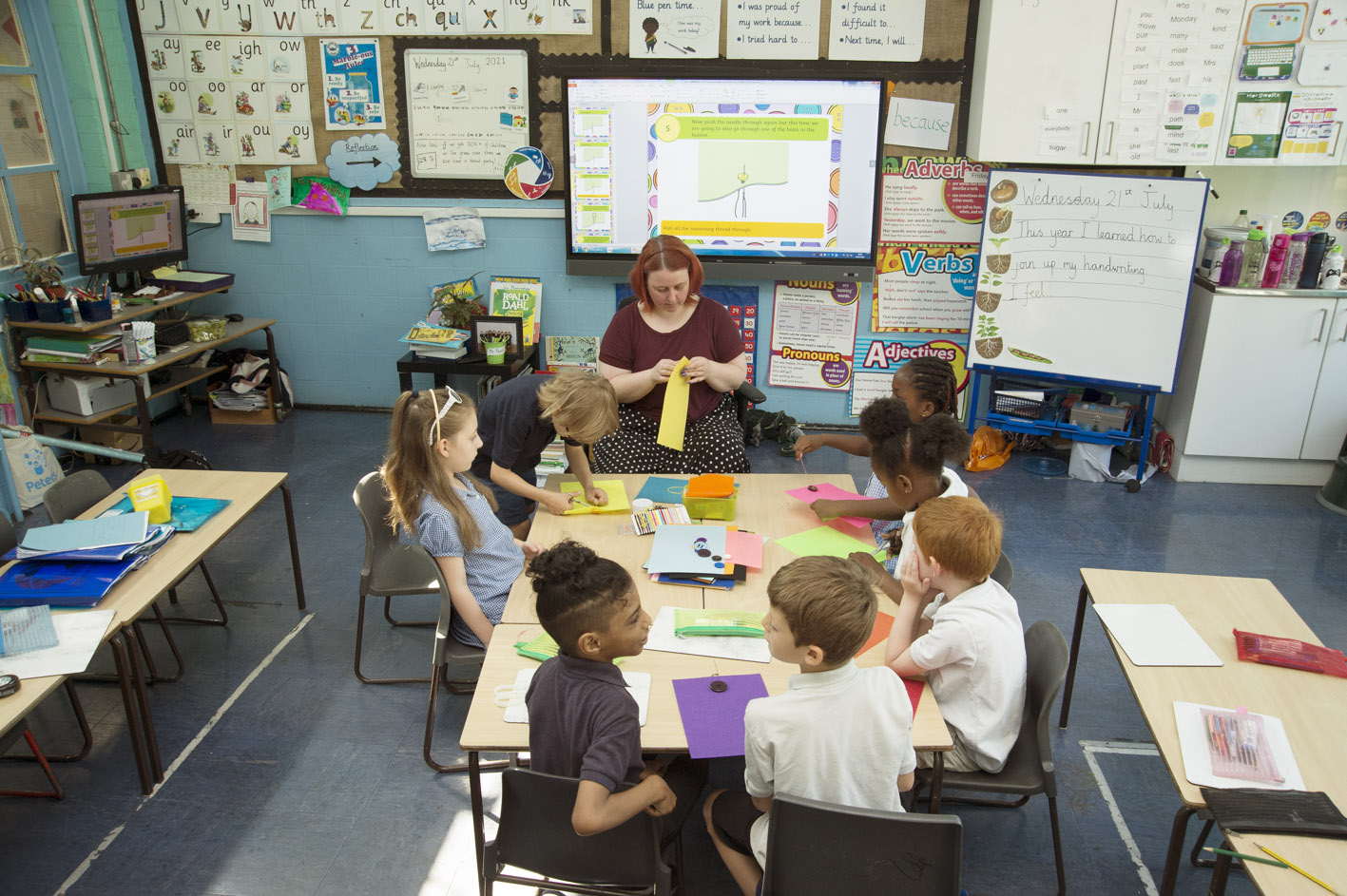 A teacher helping pupils learn to sew