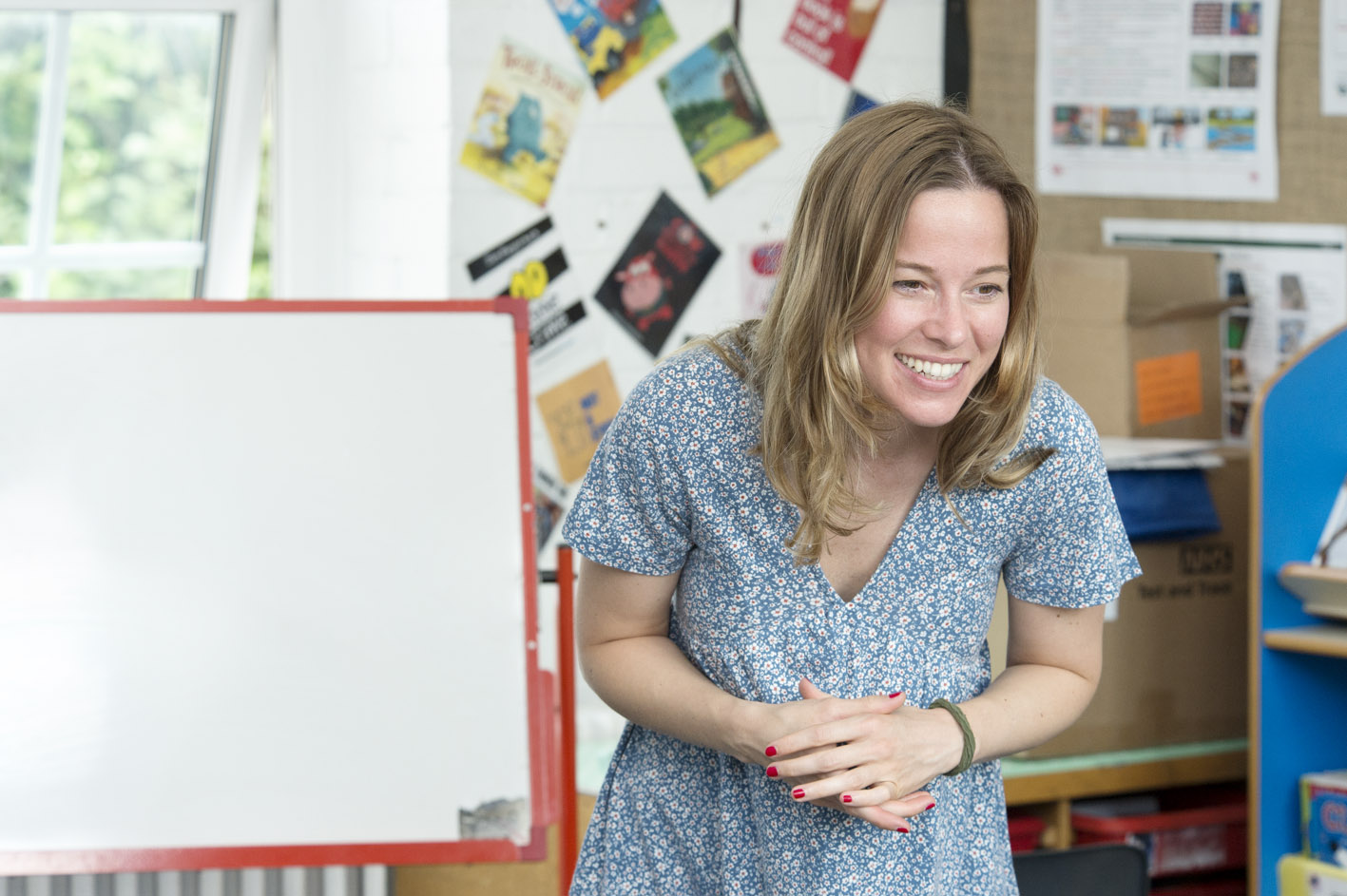 A smiling teacher speaking to pupils in the classroom 