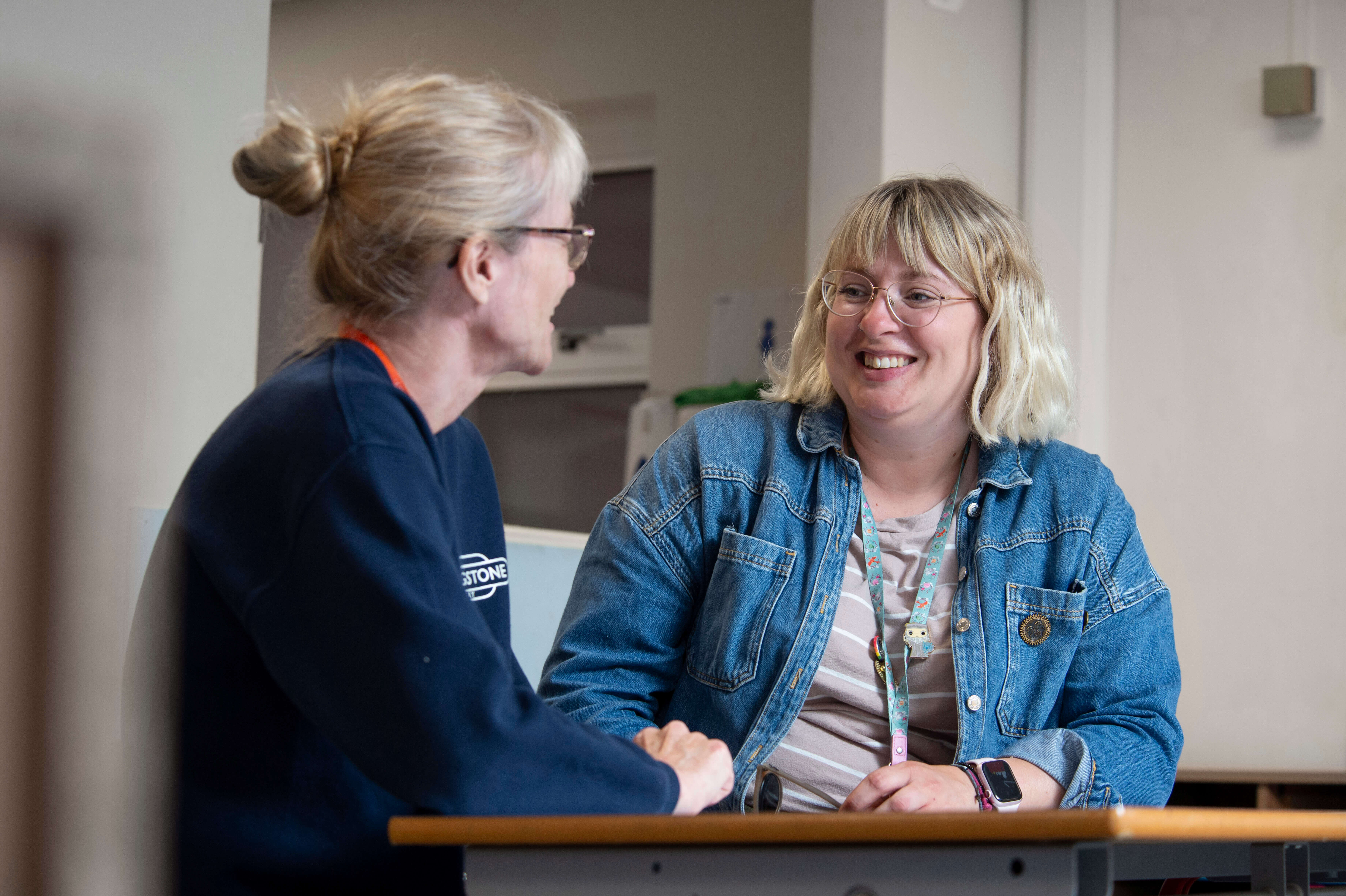 Two teachers smiling and talking at a desk