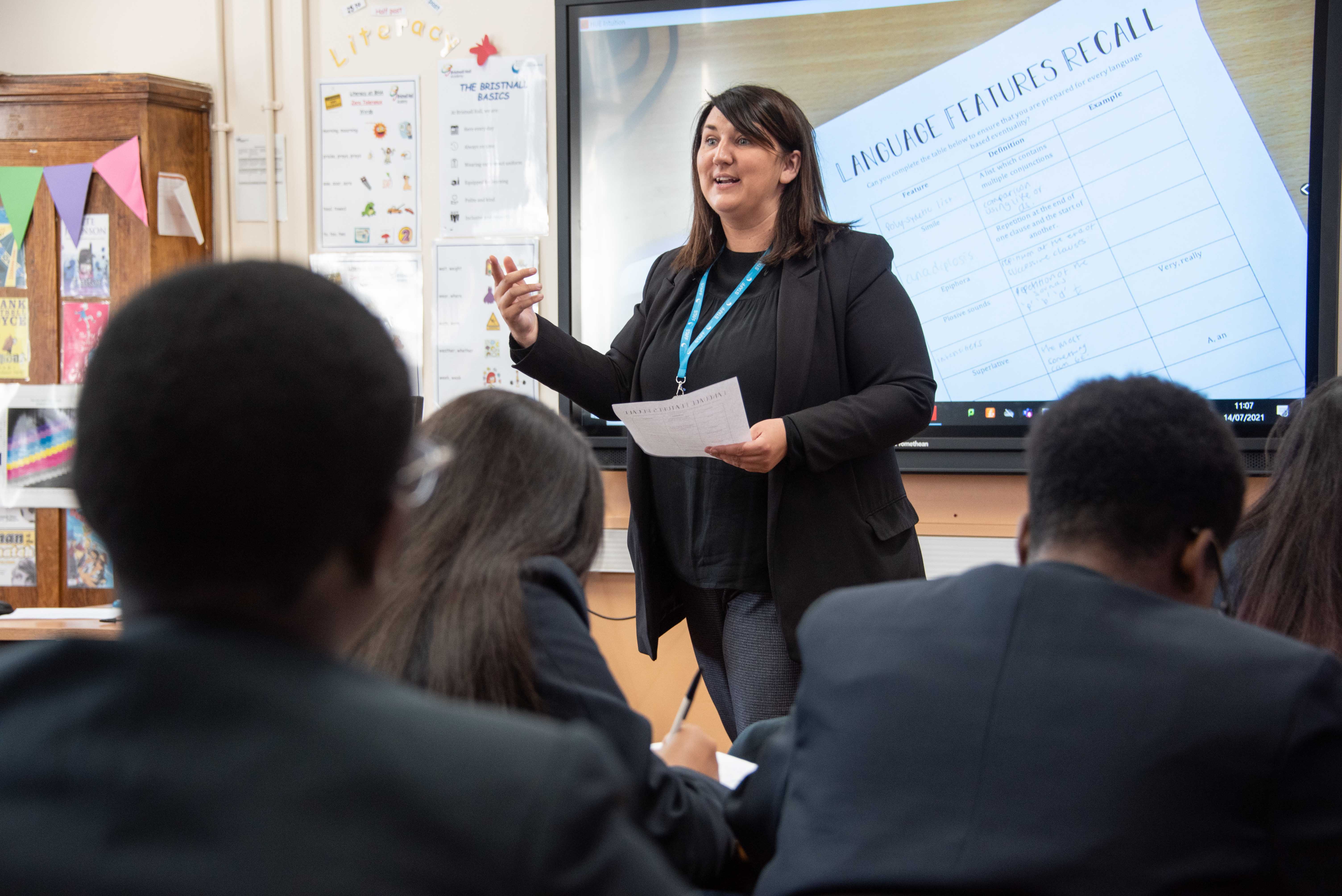 Teacher at the front of a classroom talking to her students