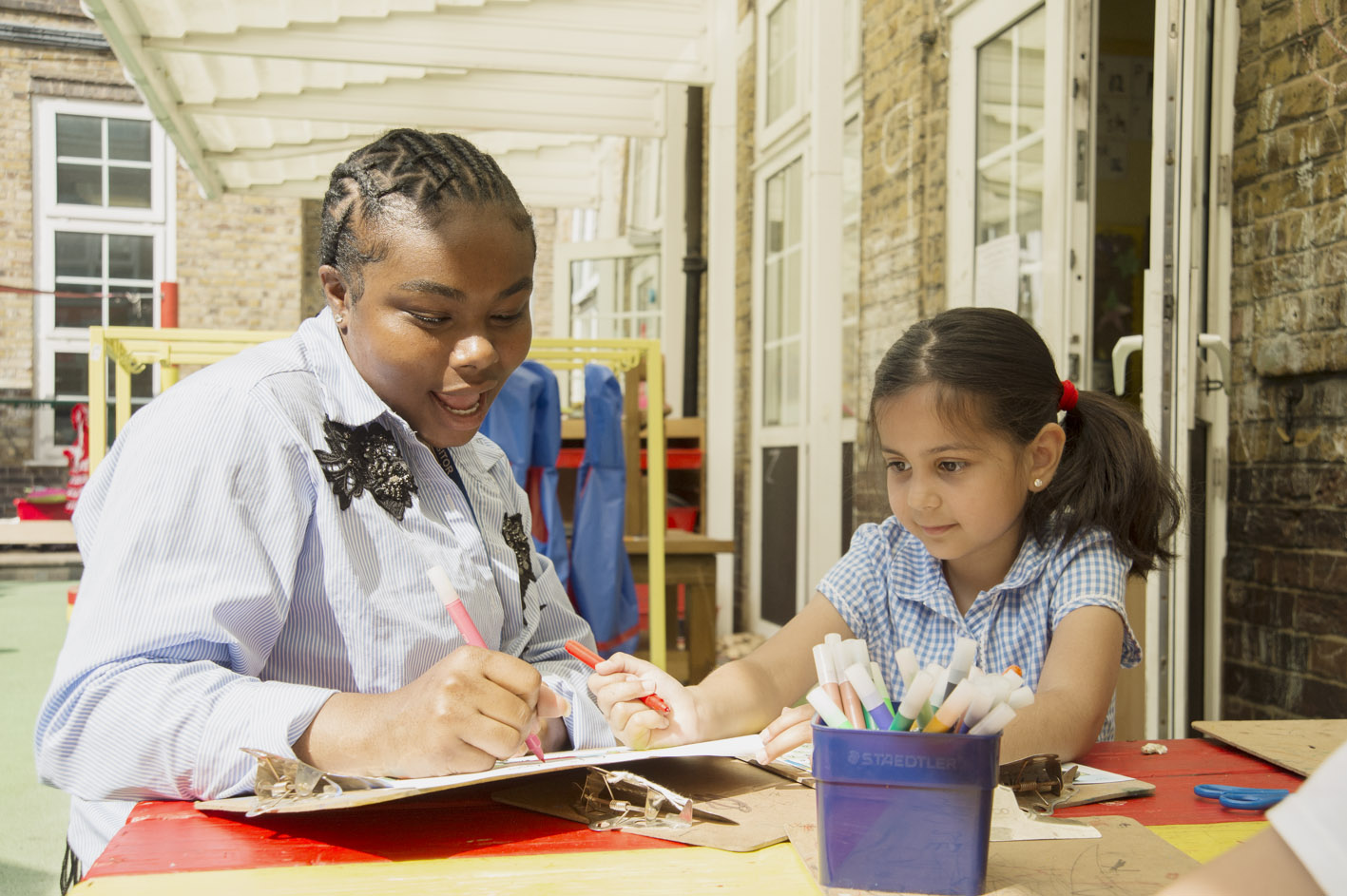 A smiling teacher helping a pupil 