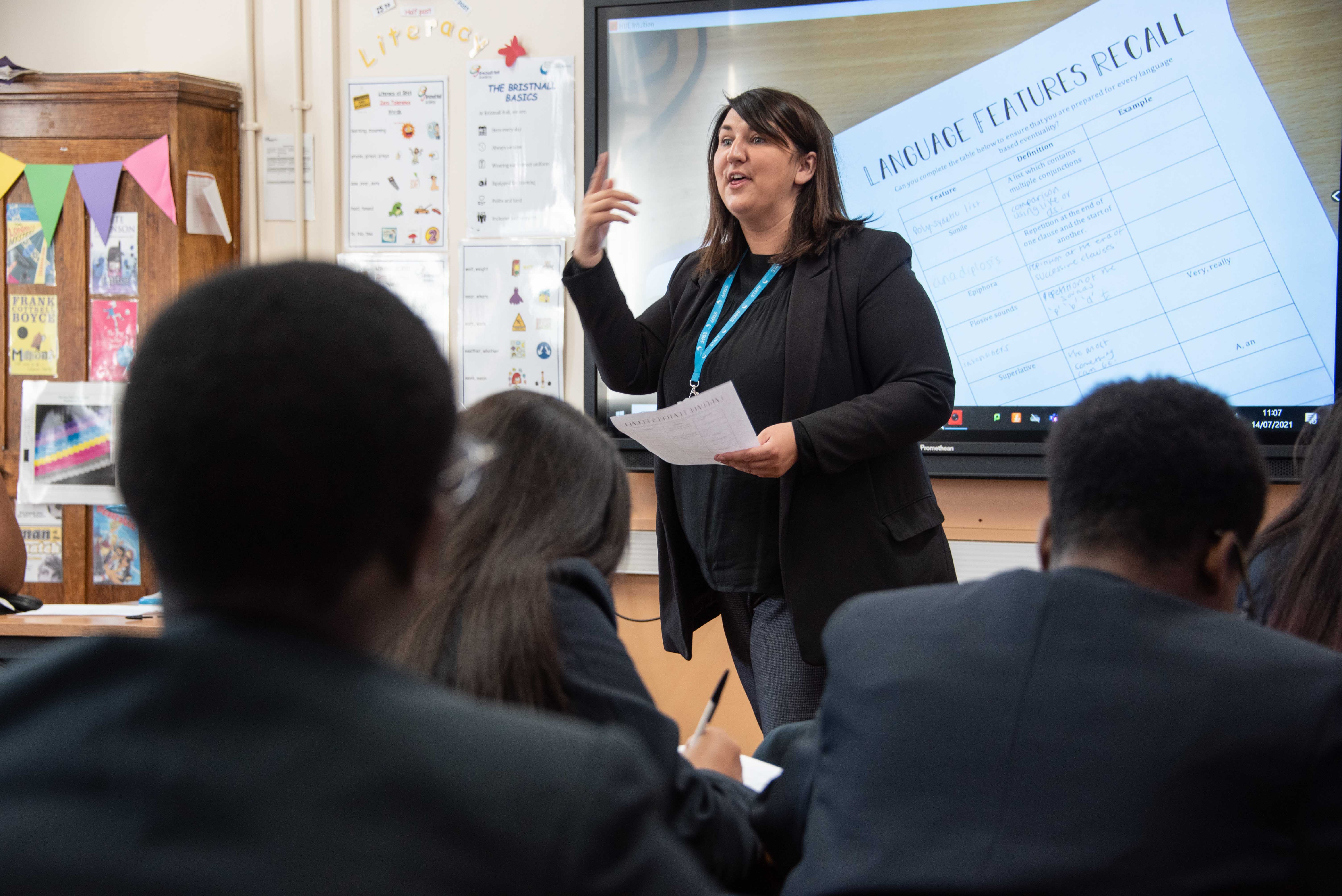 Teacher at the front of a classroom talking to her students