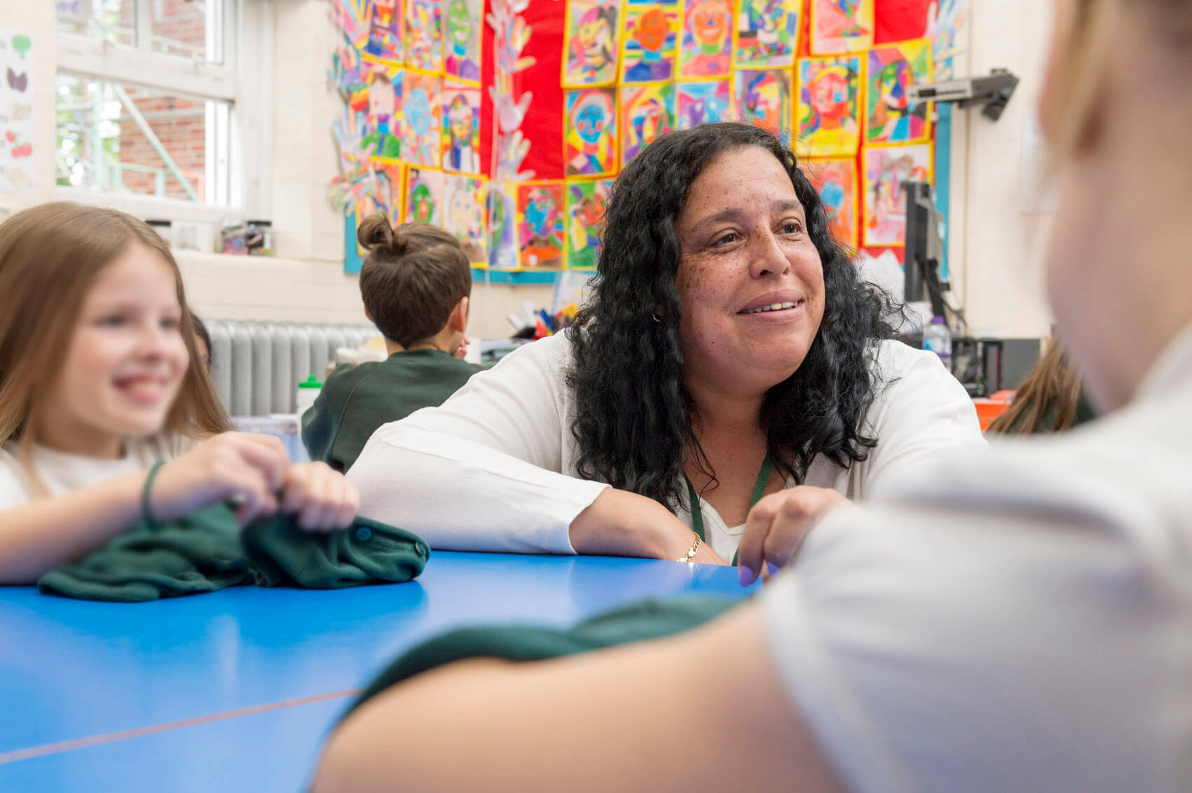 Primary school teacher talking to pupils in classroom and smiling